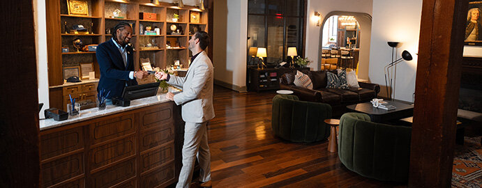 A man is being served at the reception desk in a hotel lobby.