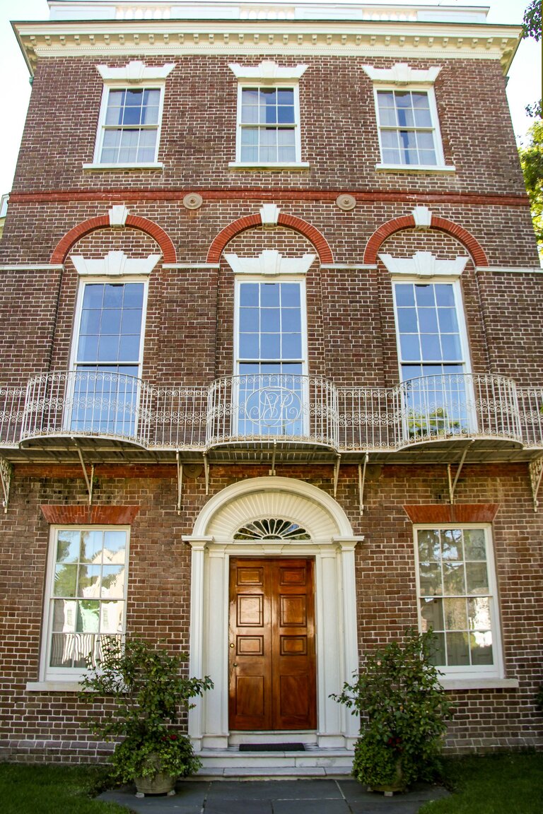 A three-story brick building with a brown door and white trim