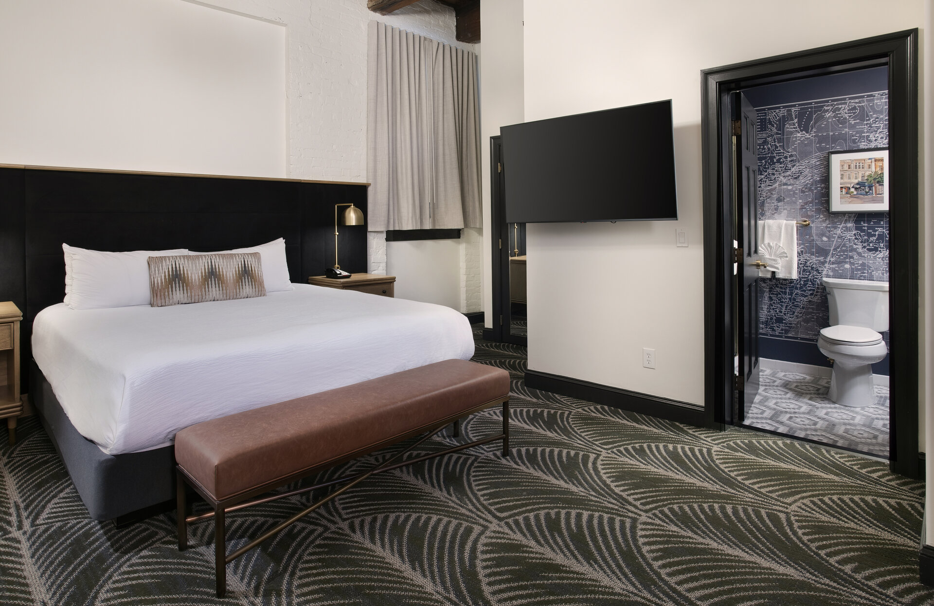 A hotel room with a bed, TV, and bathroom