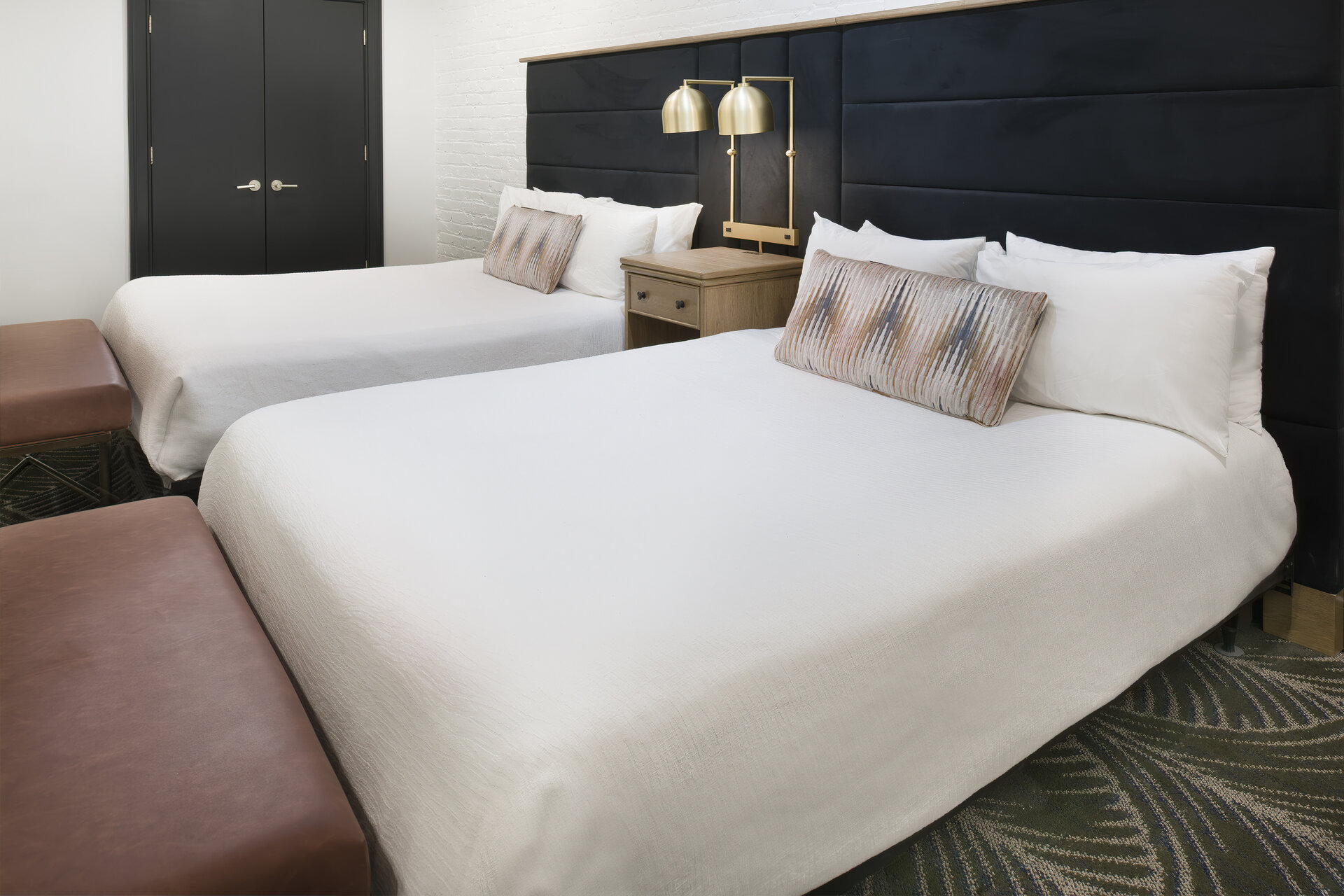 A hotel room with two twin beds, a nightstand, and a lamp.